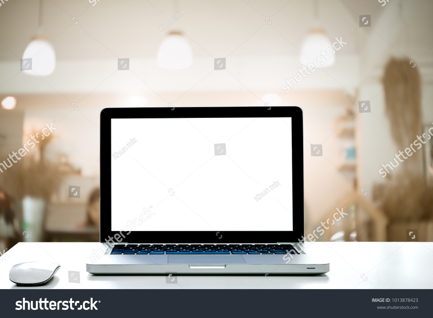 Laptop with blank screen and wireless mouse on Empty space desk white at cafe Interior blurred background.