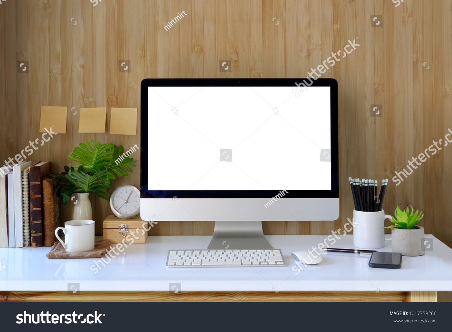 Workspace and blank screen desktop computer.Mockup desktop computer coffee mug plant and home office accessories on white desk.