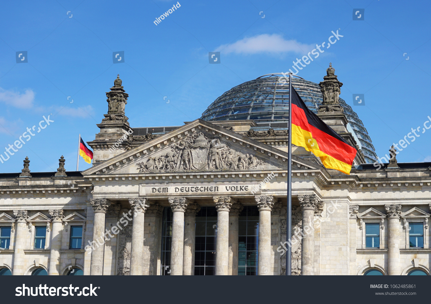 German flag waving at Bundestag building in Berlin Germany front facade view in a sunny day with blue sky.
