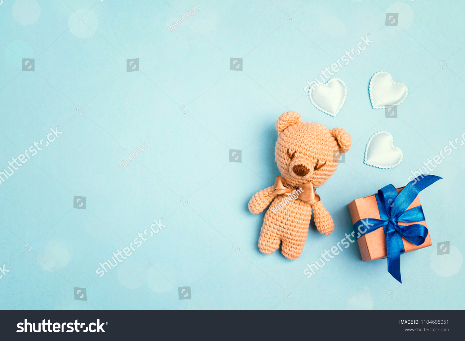 Toy bear and gift box on a blue background with copy space. Greting card concept. Top view flat lay.