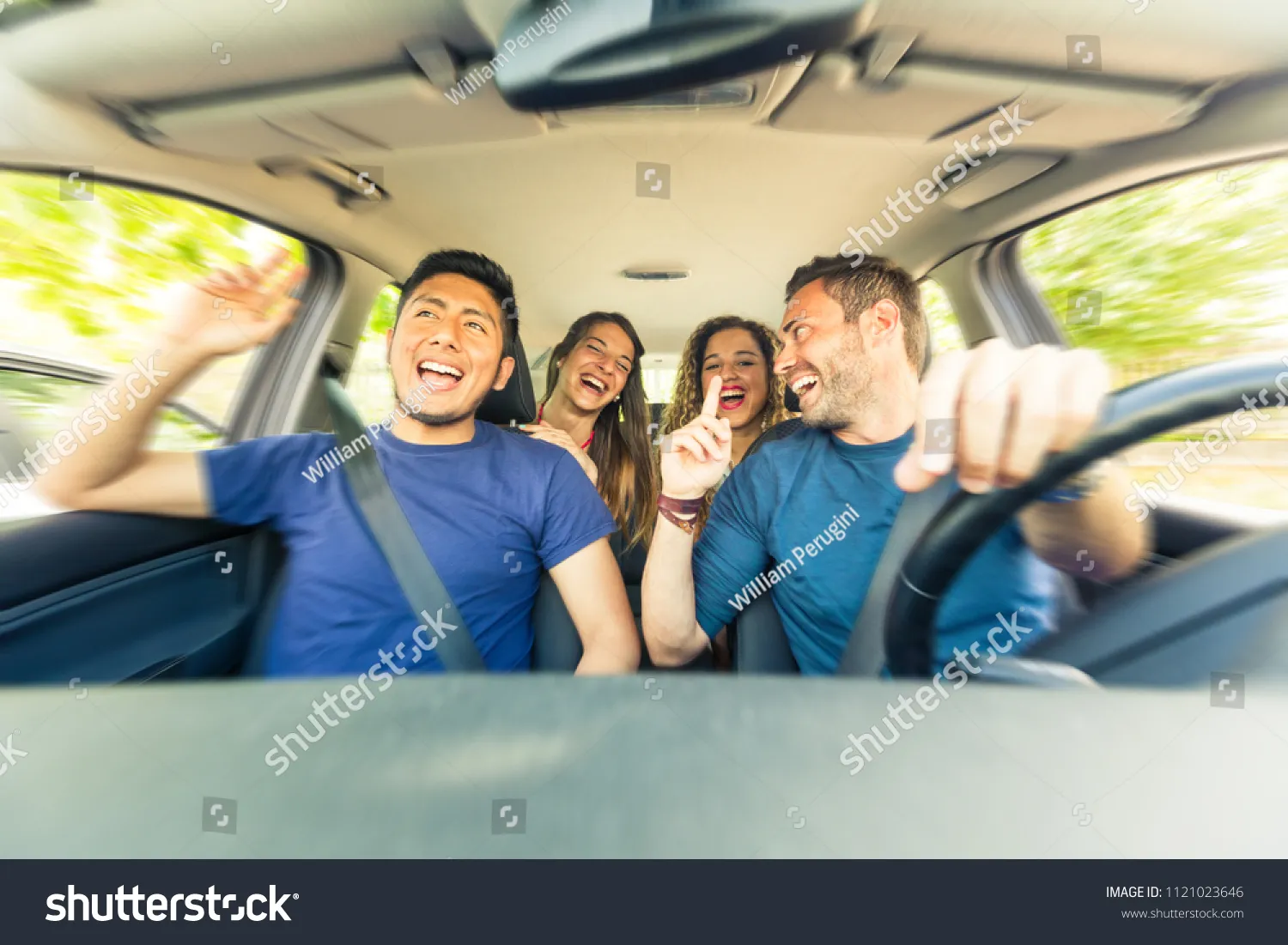 Friends inside the car singing during a road trip . Multicultural group ...