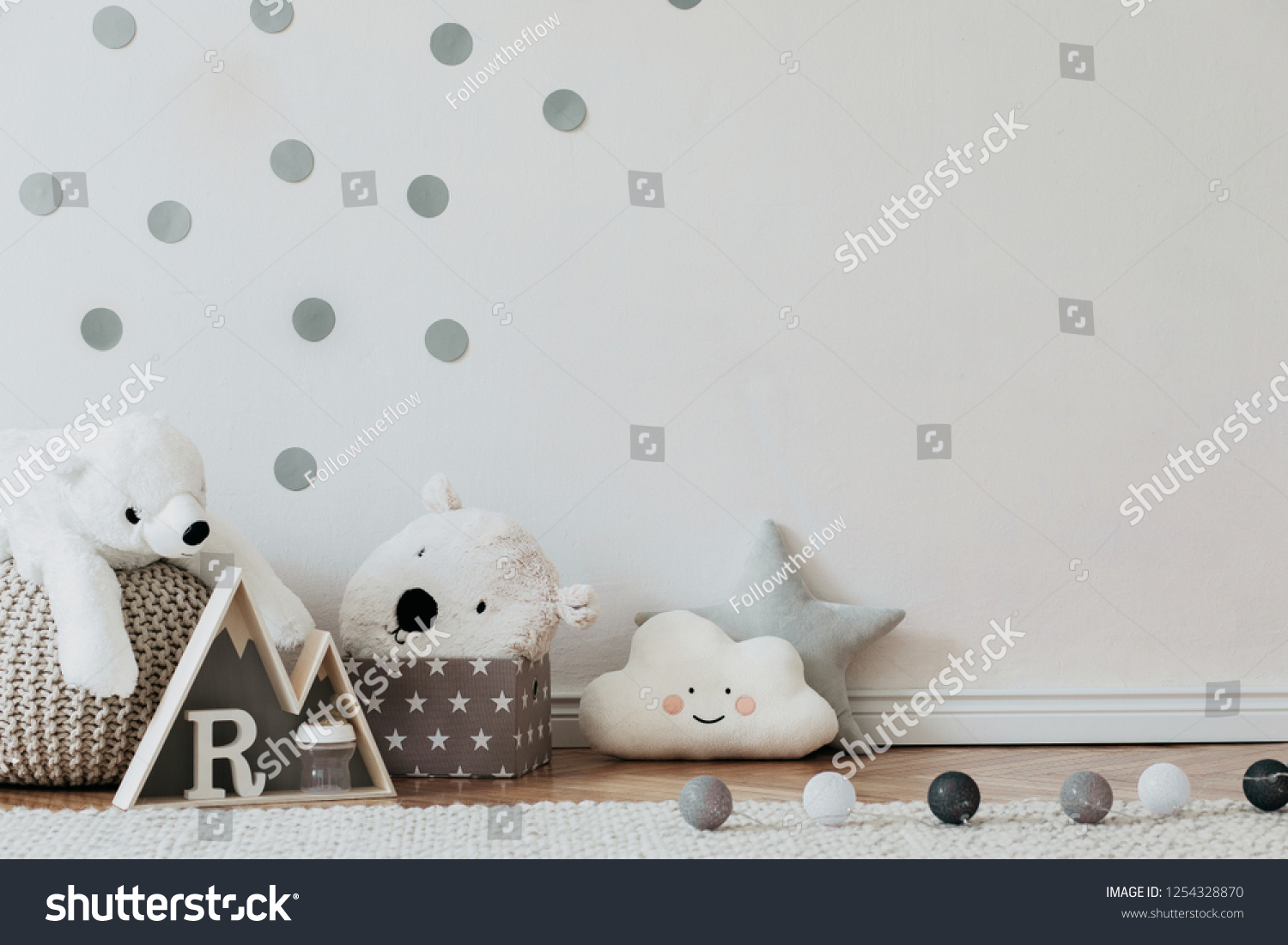 Stylish scandinavian newborn baby interior with mock up photo poster frame on the pattern wall boxes teddy bears and toys. White walls wooden accessories and toys. Copy space.