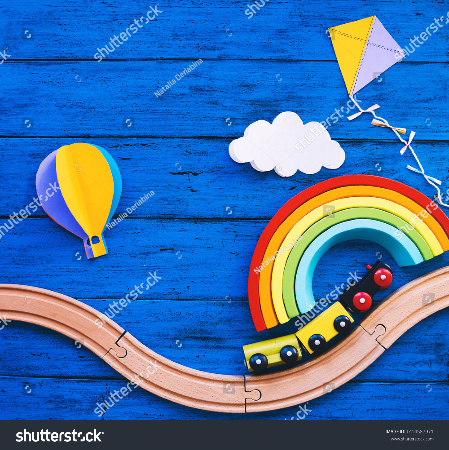 Wooden toy train railway for preschool child wood rainbow paper crafts on blue table. Waldorf or montessori school background. Kids dream travel concept. Educational toys for kindergarten children