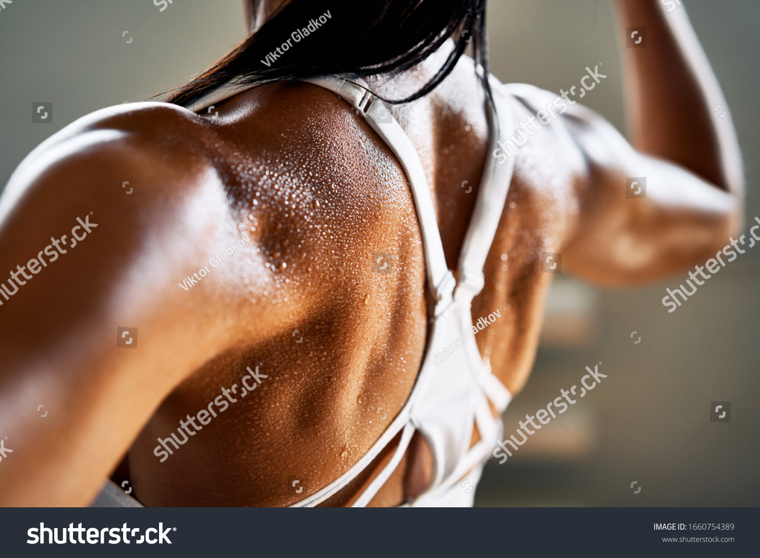 Close up of woman back with flexing her muscles in sweat on skin after workout. Female bodybuilder with perfect biceps