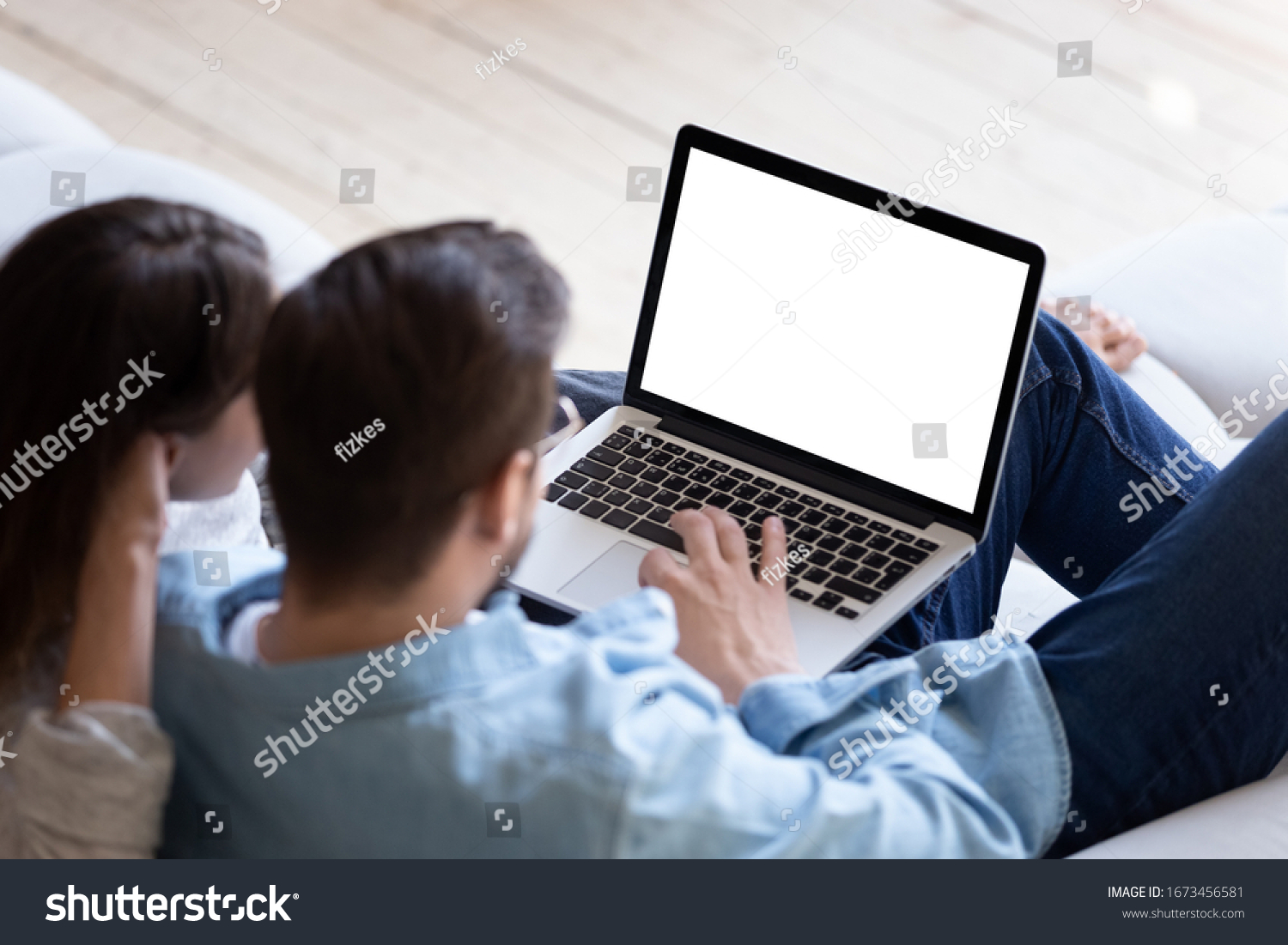 Loving couple looking at laptop screen blank white mockup close up sitting on cozy sofa young man and woman reading email message searching information in internet shopping or chatting online