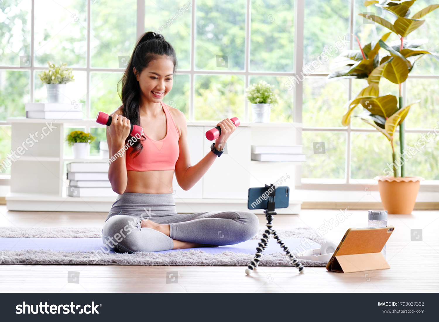 Exercise online training class at home Asian girl holding dumbbell for workout fitness Healthy asia woman training exercise by mobile phone Female sport blogger recording video by smartphone
