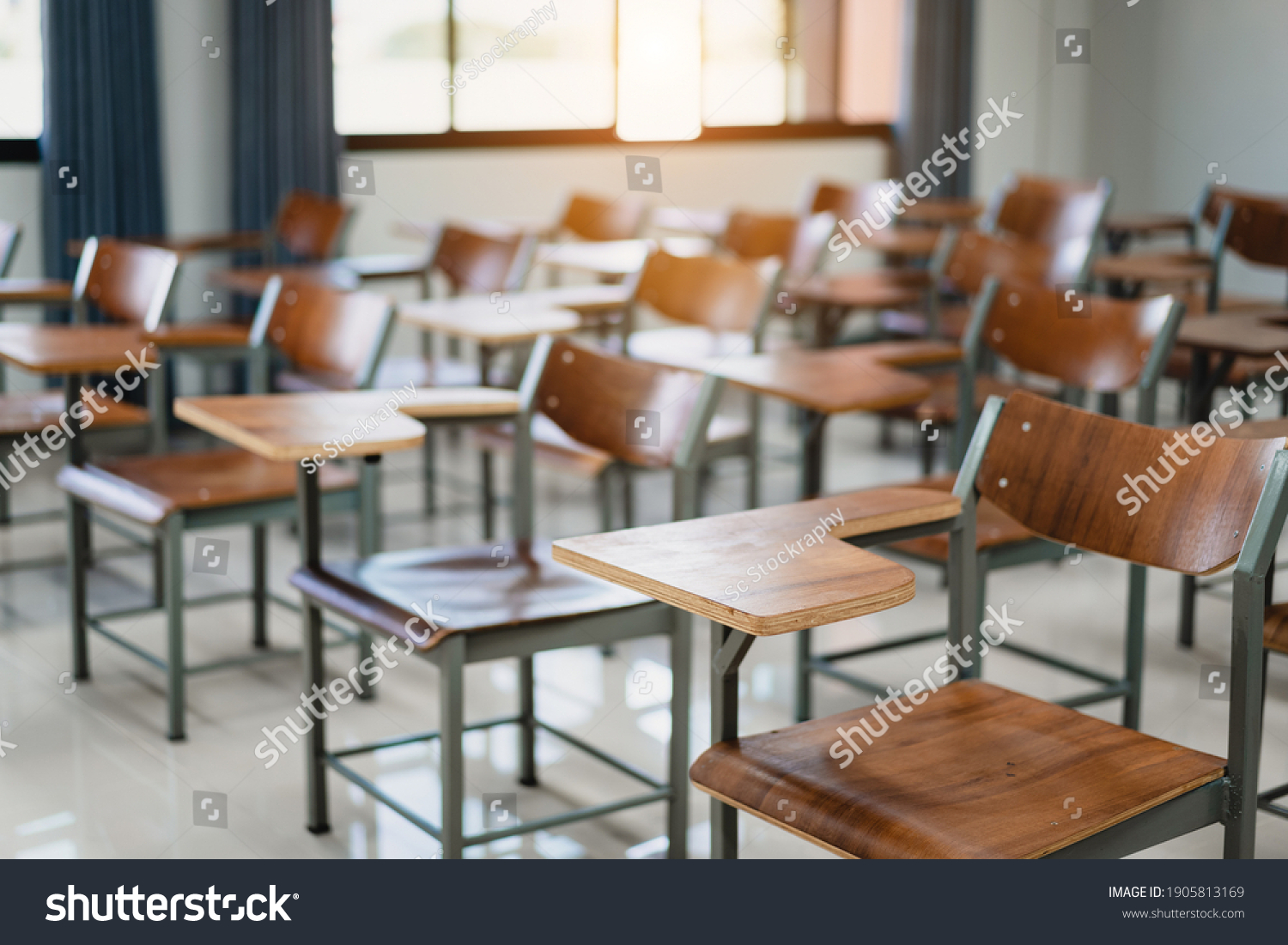 Empty university classroom with many wooden chairs. Wooden chairs well arranged in college classroom. Empty classroom with vintage tone wooden chairs. Back to school concept.