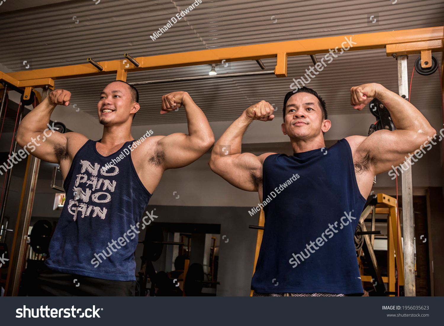Two friends enjoy a friendly posedown after training doing double bicep poses. Having fun and camaraderie at the gym.