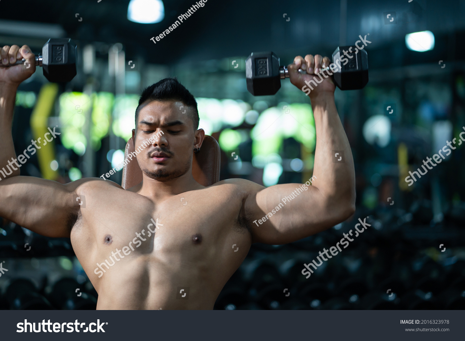 Handsome adult Caucasian men sweating while lift up the dumbbell workout for shoulder muscle part inside of fitness gym. Bodybuilding athlete sport training for body strength and good health.