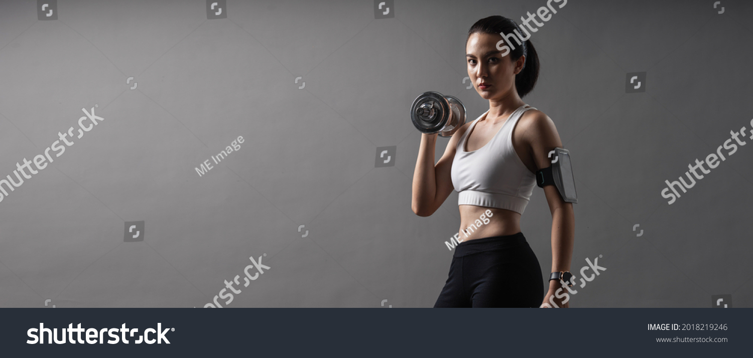 Web banner portrait athlete Asian active woman workout with dumbbell weightlifting up in studio grey background. Young female in sportswear healthy exercise.