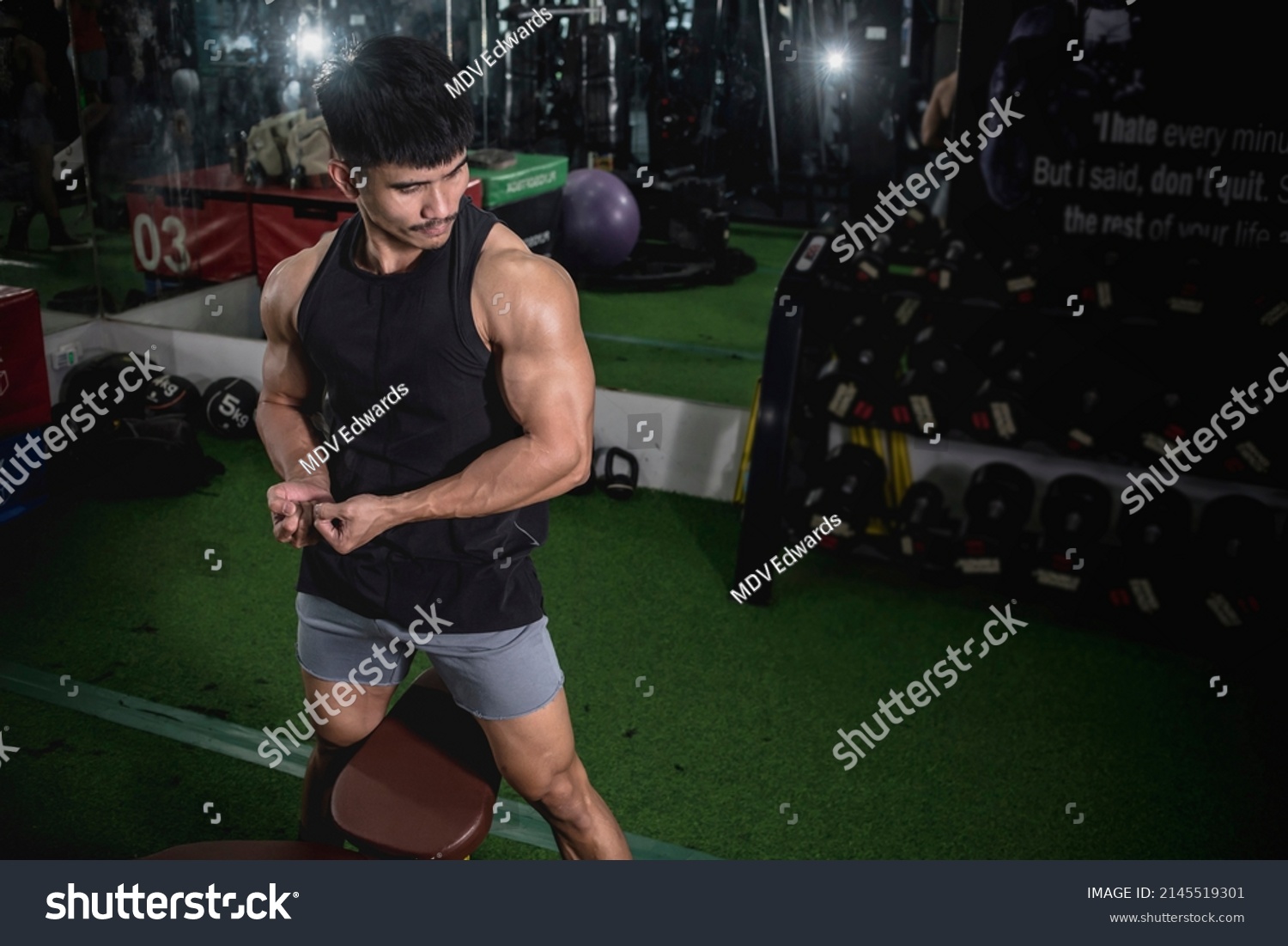 A fit man flexes his biceps and feels the pump after a vigorous arm workout. Isometeric hold at the gym.
