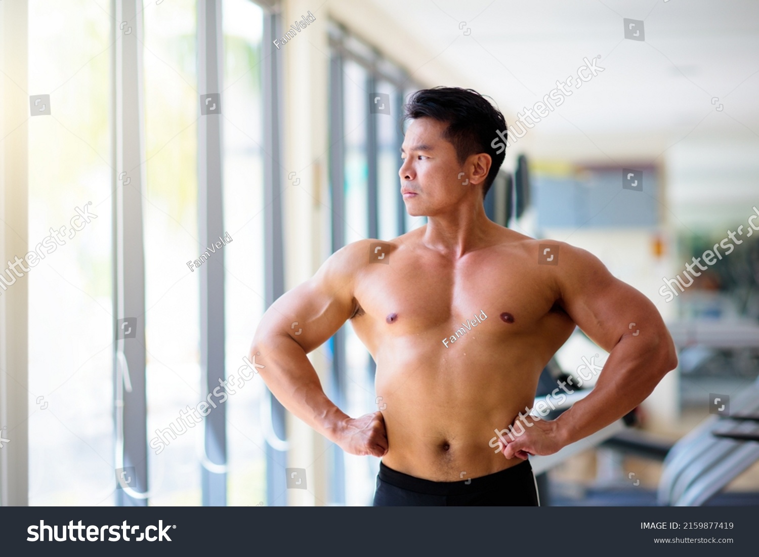 Man exercising in gym. Asian bodybuilder lifting weights. Sport and healthy activity for young male. Active Chinese athlete in training. Body building exercise work out.