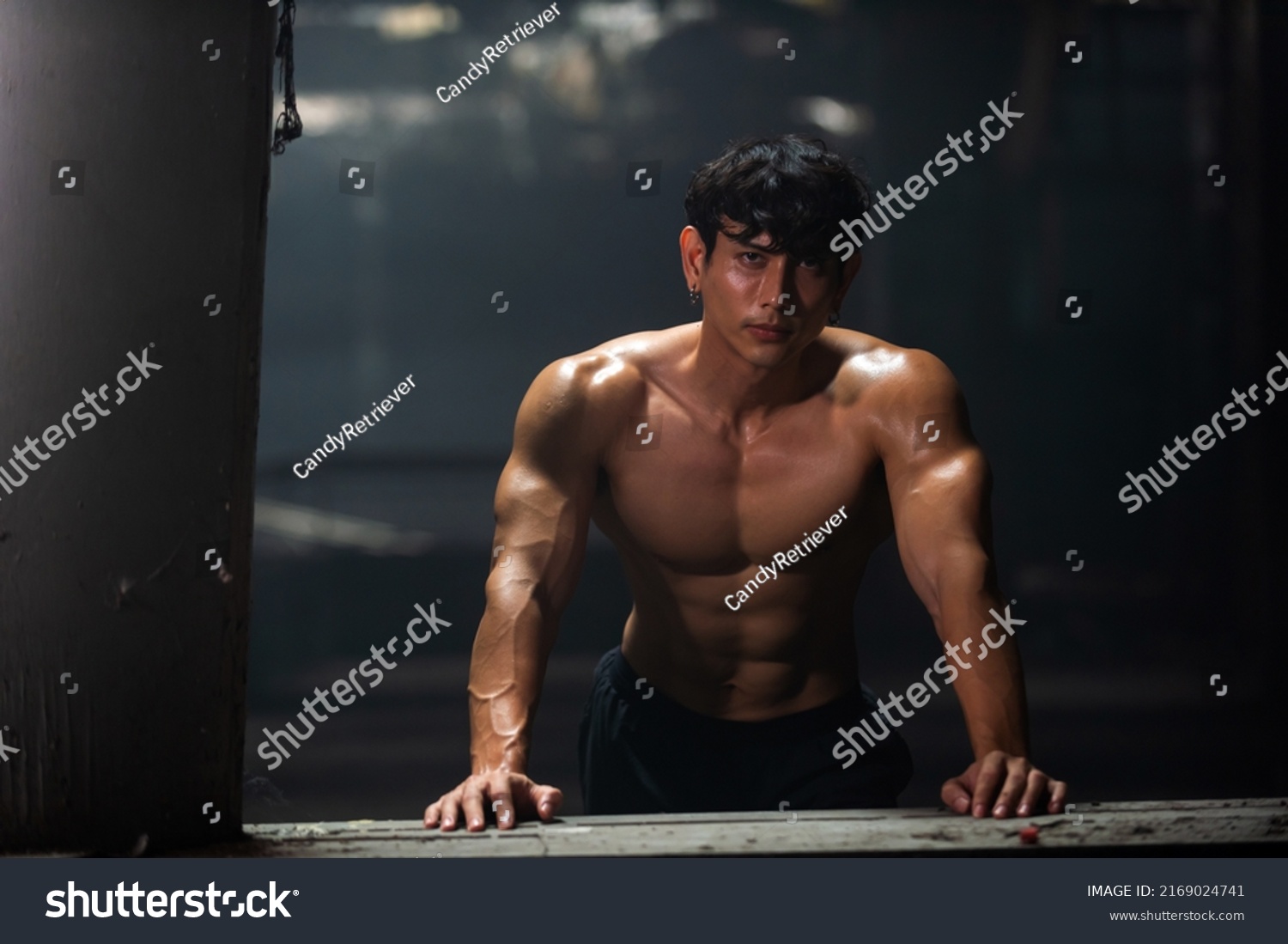 Portrait of Strong Asian sportsman athlete in sportswear do sport training workout bodybuilding exercise in abandoned building. Shirtless man bodybuilder practicing muscular build in dark place gym