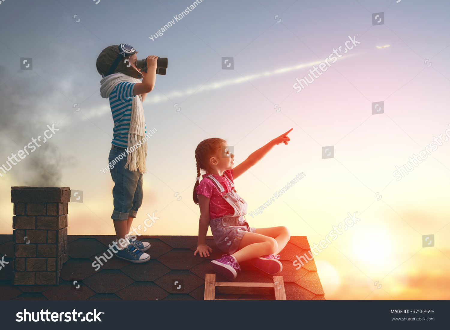 Two little children playing on the roof of the house and looking at the sky and dreaming of becoming a pilots.