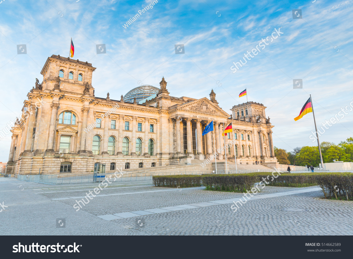 German Reichstag the German parliament building in Berlin at sunset. Some german flags and one European waving. Politics and architecture concepts.