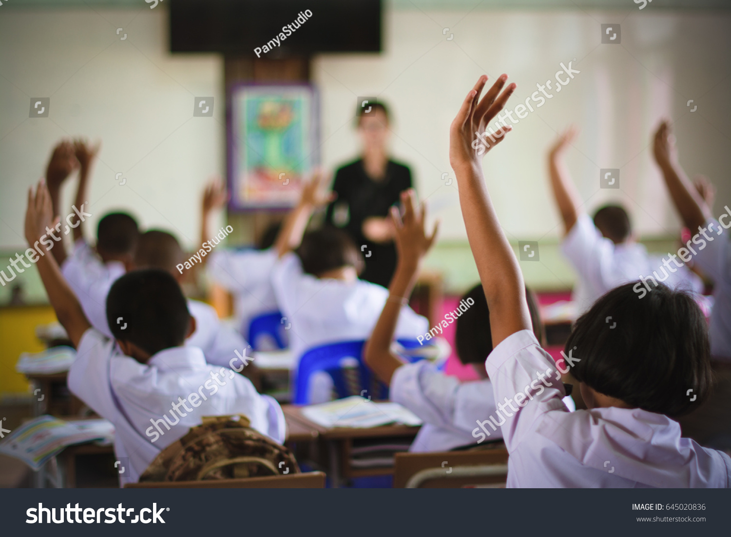education elementary school learning and people concept - group of school kids with teacher standing in classroom and raising hands
