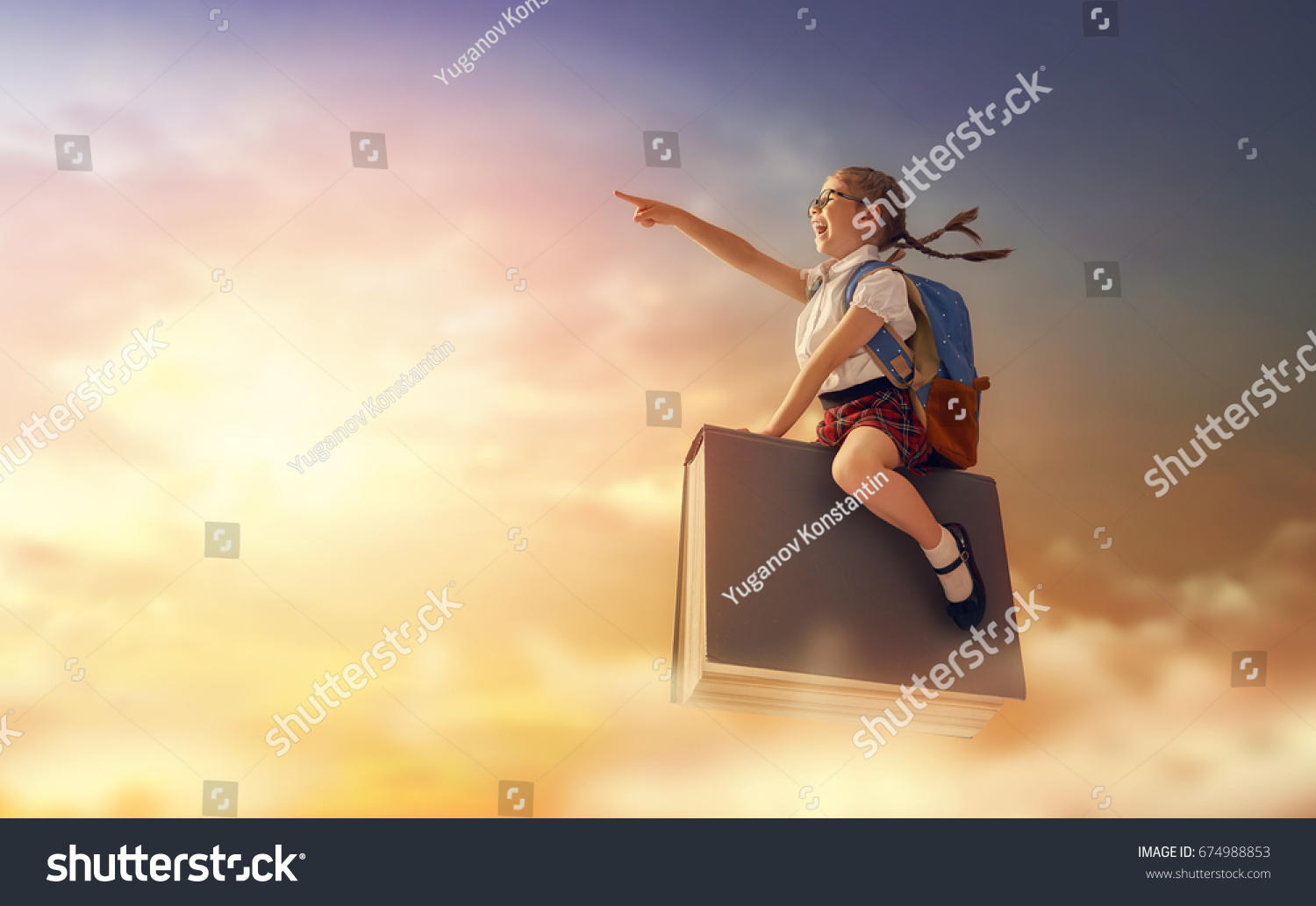 Back to school! Happy cute industrious child flying on the book on background of sunset sky. Concept of education and reading. The development of the imagination.