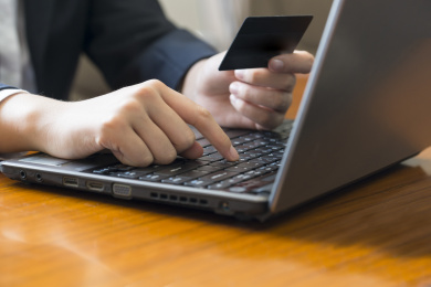 网上购物，女子手持信用卡和使用笔记本电脑