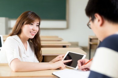 两个亚洲学生讨论平板电脑内容时，研究课堂