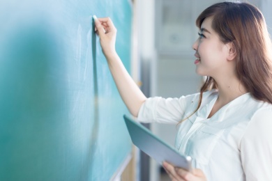 年轻漂亮的女孩在教室黑板绿