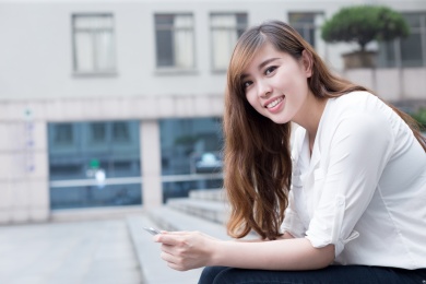 亚洲美丽的女学生使用的校园手机