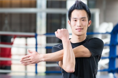 在现代化的健身房年轻的亚洲男子做瑜伽