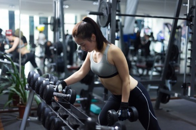 年轻的亚洲女孩在现代化的健身房锻炼身体