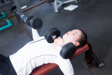 在现代化的健身房年轻的亚洲女孩保持哑铃