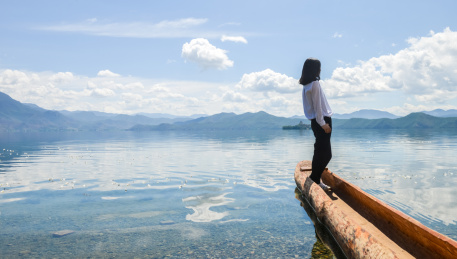 年轻女性站在传统独木舟上仰望天空 云南丽江