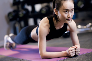 一名年轻女性在健身房做平板支撑
