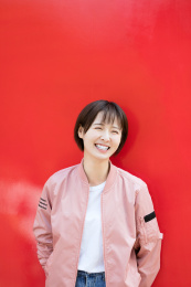 一位年轻女孩站在红色背景墙前