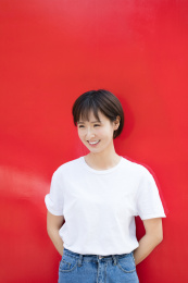 一位年轻女孩站在红色背景墙前