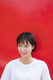 一位年轻女孩站在红色背景墙前