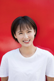 一位年轻女孩站在红色背景墙前