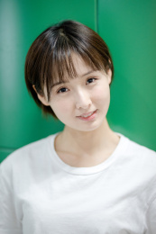 一位年轻女孩站在绿色背景墙前