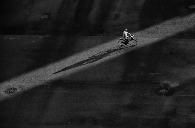 马路上光影中骑车的老人