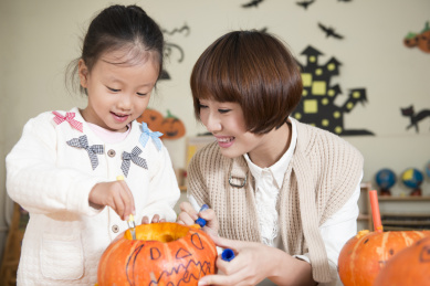 幼儿园的老师和女孩的雕刻南瓜
