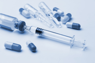 玻璃注射器和药瓶放在白色背景前