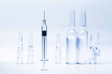 玻璃注射器和药瓶放在白色背景前