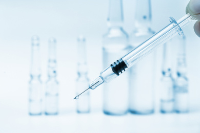 玻璃注射器和药瓶放在白色背景前