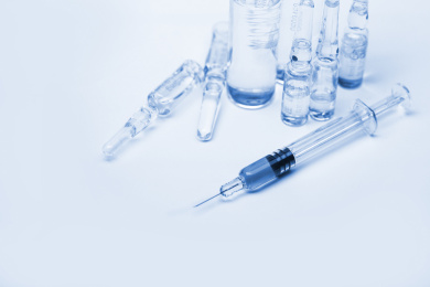 玻璃注射器和药瓶放在白色背景前