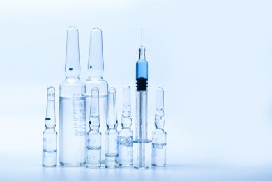 玻璃注射器和药瓶放在白色背景前