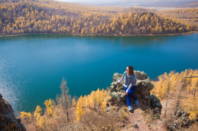 坐在阿尔山驼峰岭悬崖上的女性