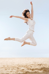 快乐的年轻女性在海边跳跃