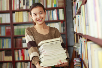漂亮的女大学生阅读的书在图书馆