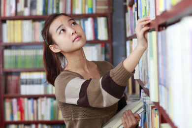 漂亮的女大学生阅读的书在图书馆