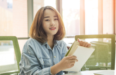 年轻美丽的女孩在桌子前看书