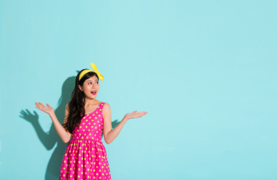 混血亚洲中国模特穿着可爱诱人的礼服和展示商场与选择的姿态被隔绝在蓝色背景最新的购物信息。