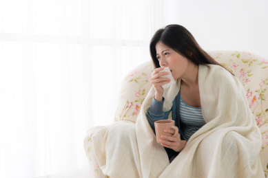 痛苦的年轻女子坐在扶手椅沙发上放松和咳嗽时，她生病了。