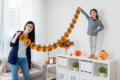 幸福的家庭准备的万圣节，年轻妈妈和她的孩子们成功挂上装饰在家庆祝节日。